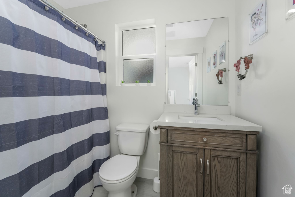 Bathroom with a shower with curtain, baseboards, toilet, and vanity