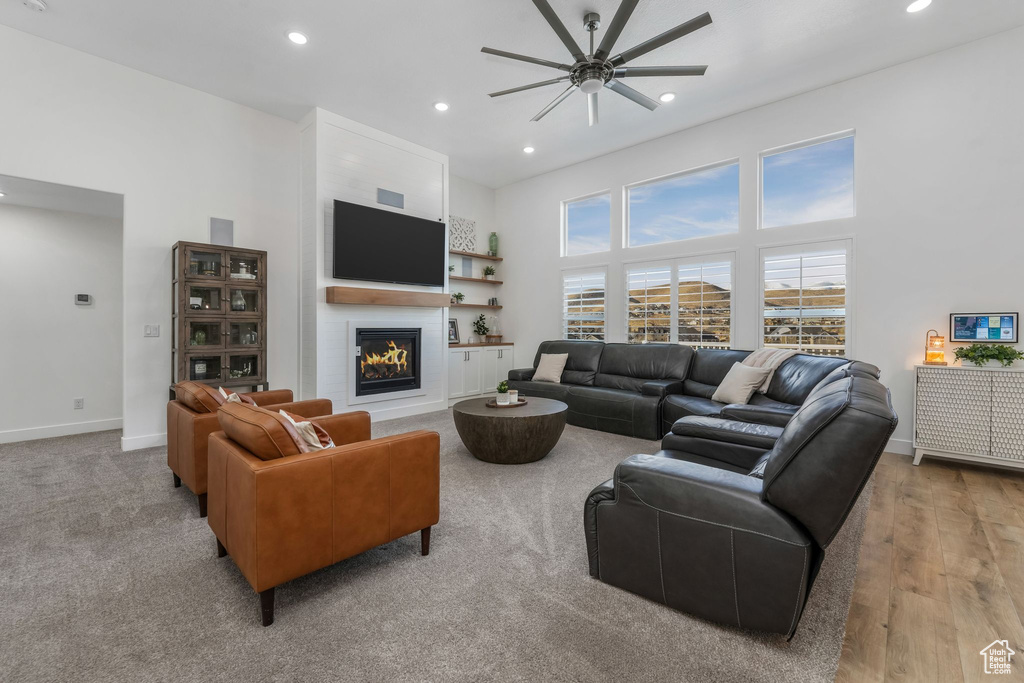 Living area with a high ceiling, recessed lighting, baseboards, and a warm lit fireplace