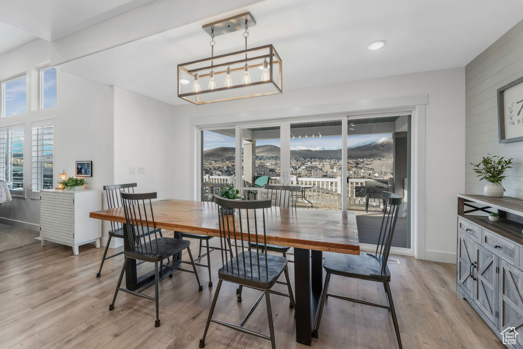 Dining area featuring baseboards, light wood-style floors, an inviting chandelier, and wooden walls