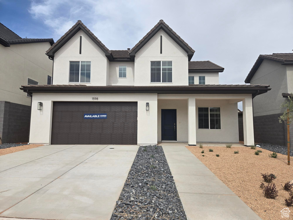 View of front of house featuring an attached garage, concrete driveway, a tile roof, stucco siding, and covered porch