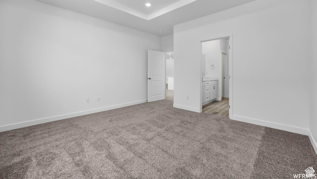 Unfurnished bedroom featuring recessed lighting, baseboards, ensuite bathroom, and light carpet