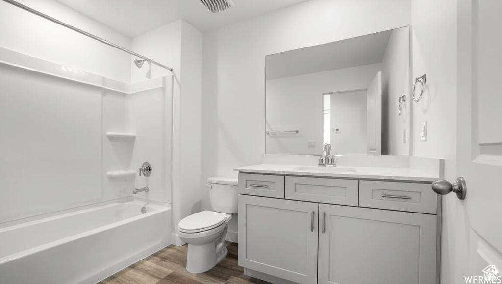 Bathroom featuring visible vents, toilet, wood finished floors, shower / bathing tub combination, and vanity