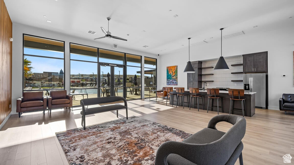 Living room with light wood-style flooring, a ceiling fan, visible vents, and baseboards