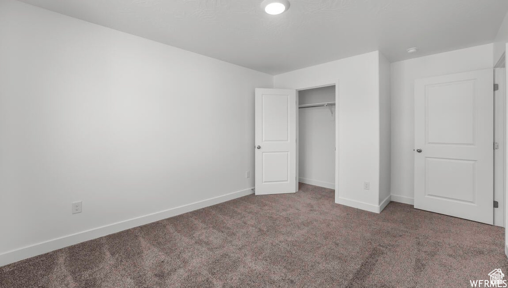 Unfurnished bedroom featuring carpet flooring, baseboards, and a closet