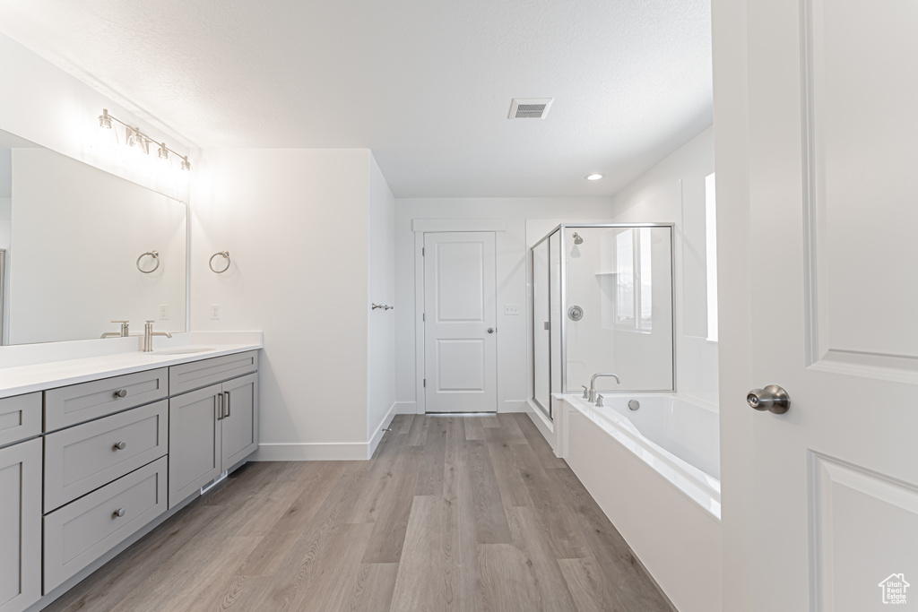 Bathroom with vanity, a stall shower, wood finished floors, and a bath