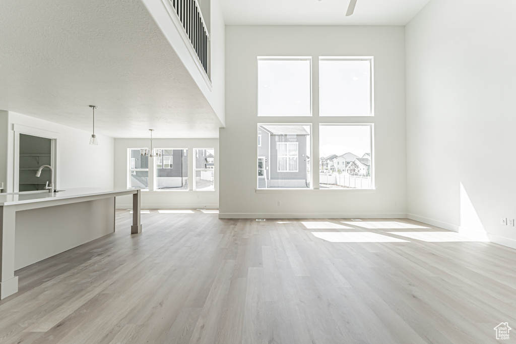 Unfurnished living room featuring light wood-style floors, baseboards, and ceiling fan