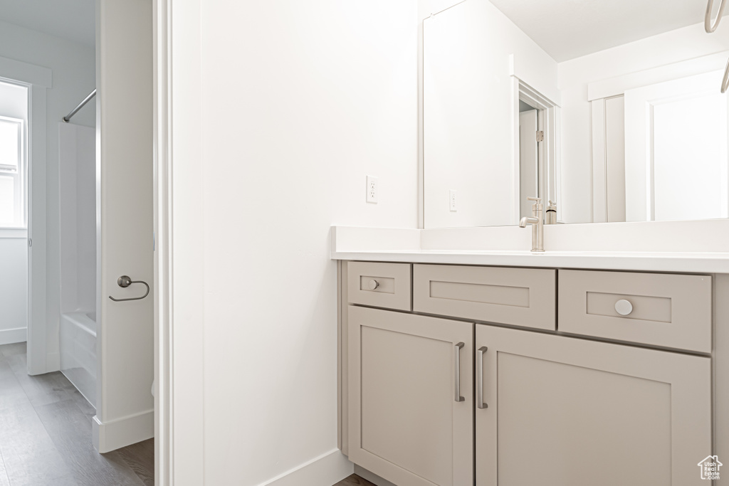 Full bathroom featuring vanity, wood finished floors,  shower combination, and baseboards