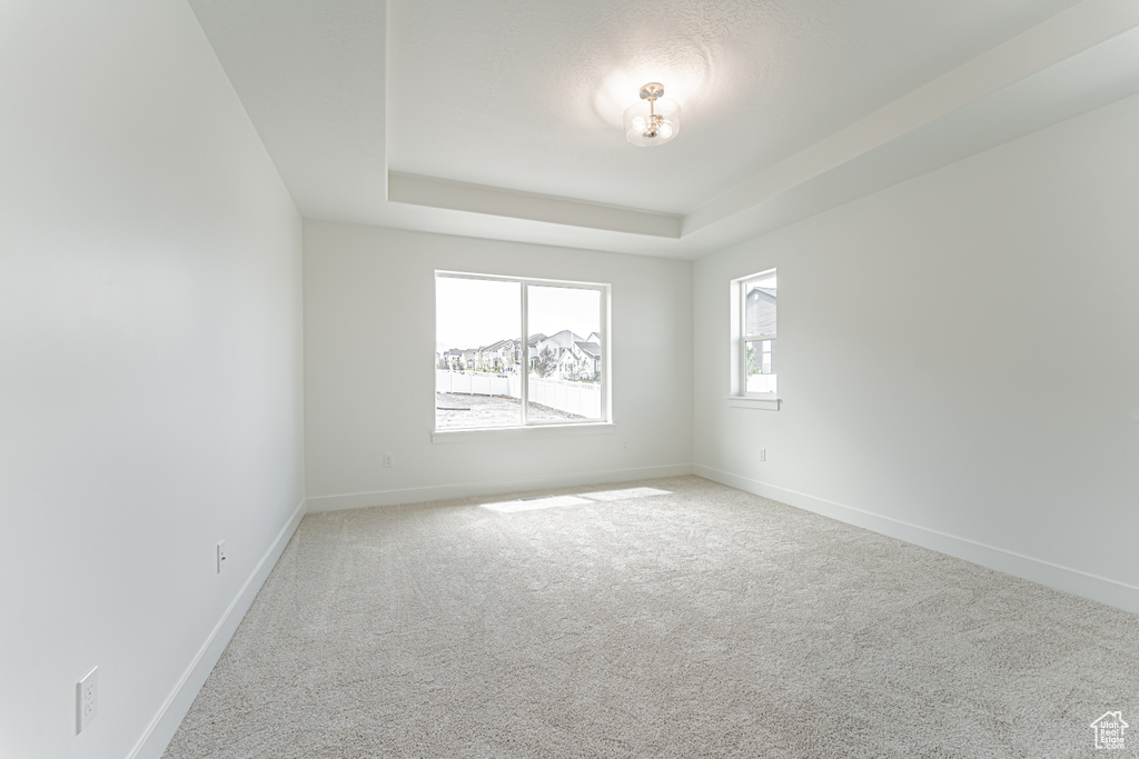 Carpeted empty room featuring baseboards and a raised ceiling