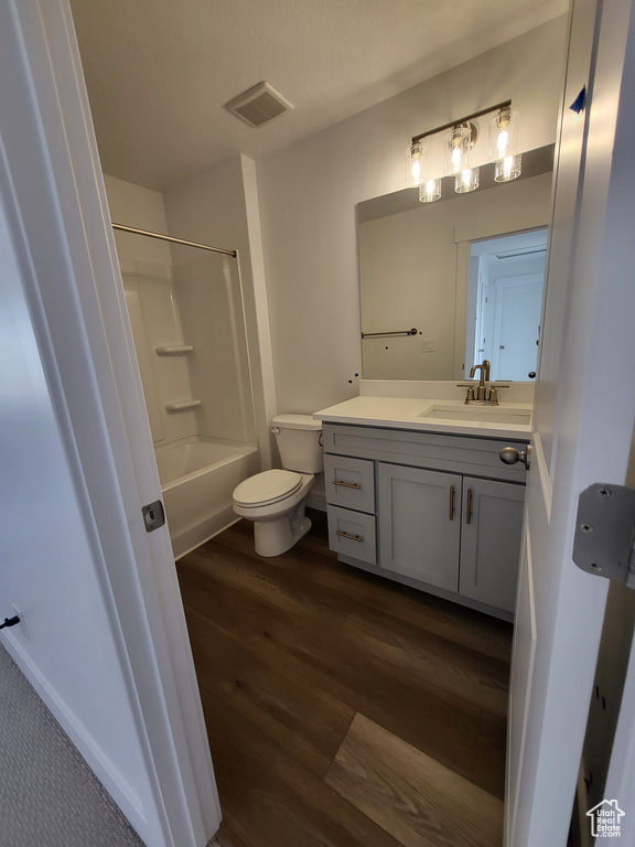 Full bathroom featuring vanity, shower / tub combination, toilet, visible vents, and wood finished floors
