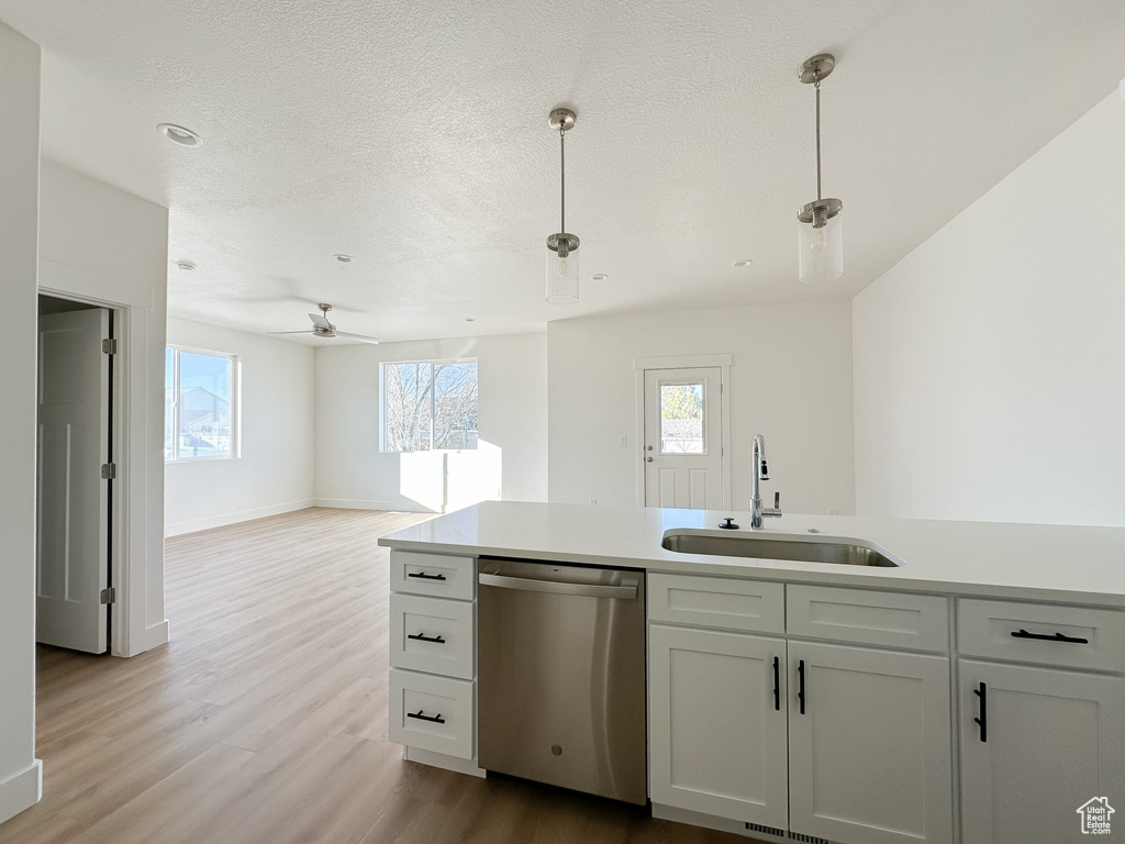 Kitchen with a sink, open floor plan, wood finished floors, light countertops, and dishwasher