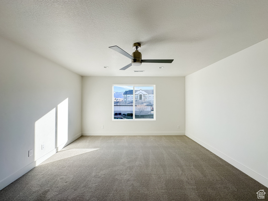 Unfurnished room with visible vents, light carpet, a ceiling fan, a textured ceiling, and baseboards