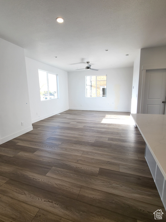 Unfurnished living room featuring a ceiling fan, baseboards, recessed lighting, and dark wood finished floors