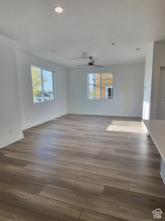 Unfurnished living room featuring recessed lighting, ceiling fan, baseboards, and wood finished floors