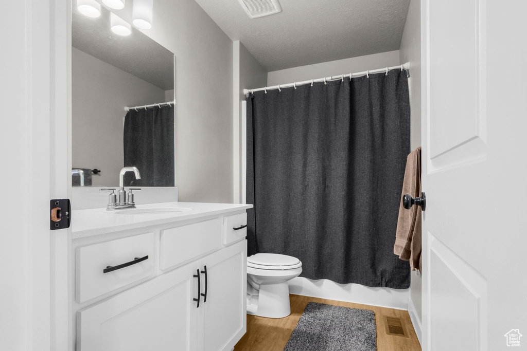 Full bathroom featuring visible vents, toilet, vanity, and wood finished floors