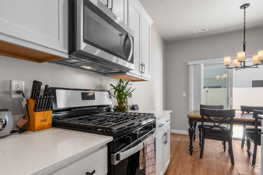 Kitchen featuring visible vents, light countertops, light wood-style floors, appliances with stainless steel finishes, and white cabinetry