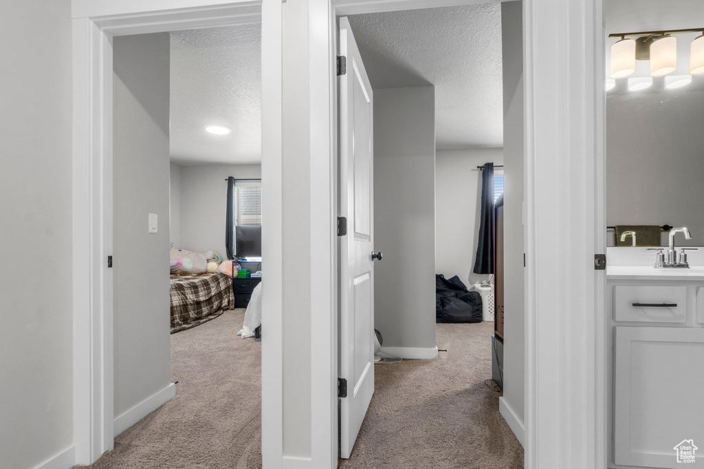 Corridor with carpet, baseboards, and a textured ceiling