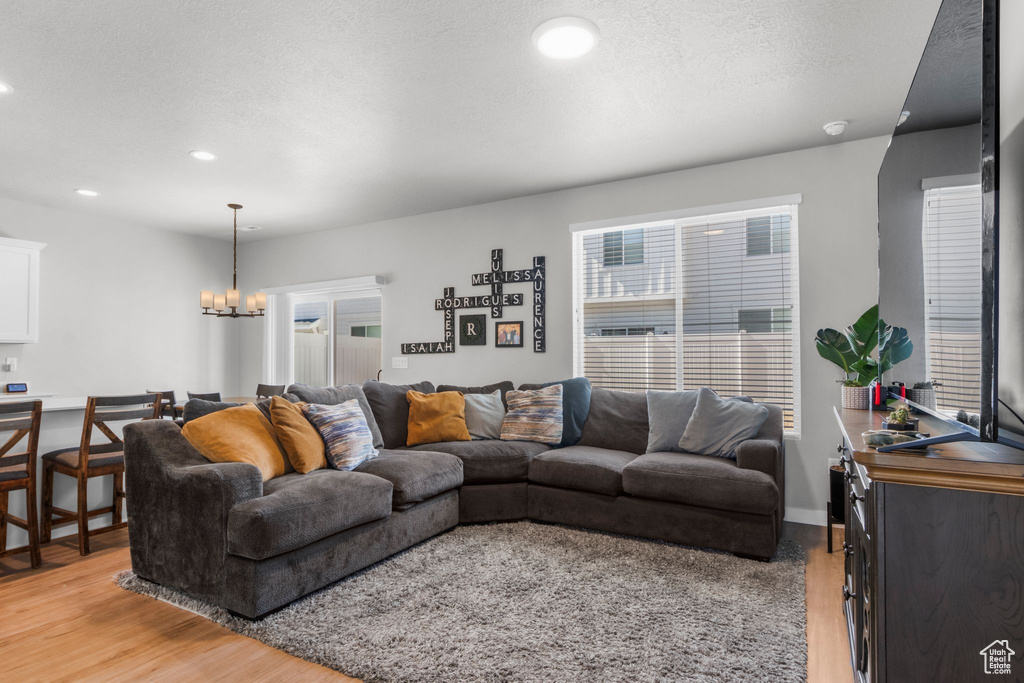 Living area featuring recessed lighting, a notable chandelier, light wood-style flooring, and a textured ceiling