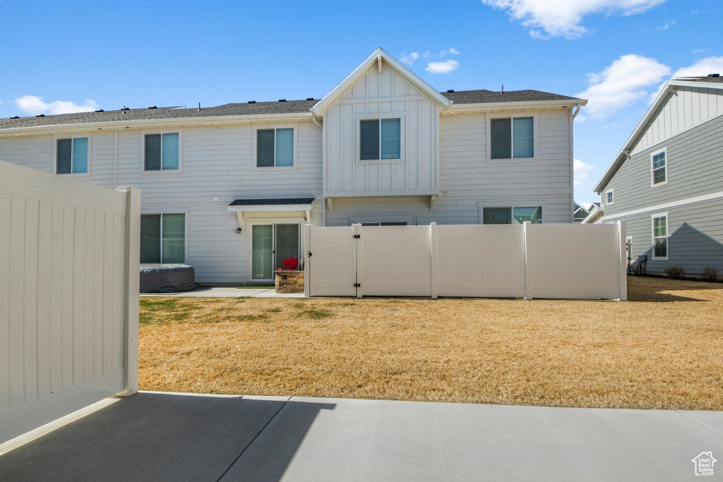 Rear view of property featuring a lawn, board and batten siding, and fence