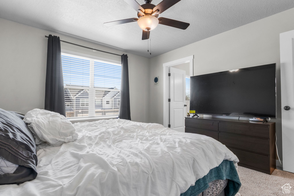 Bedroom featuring light carpet, a textured ceiling, and a ceiling fan