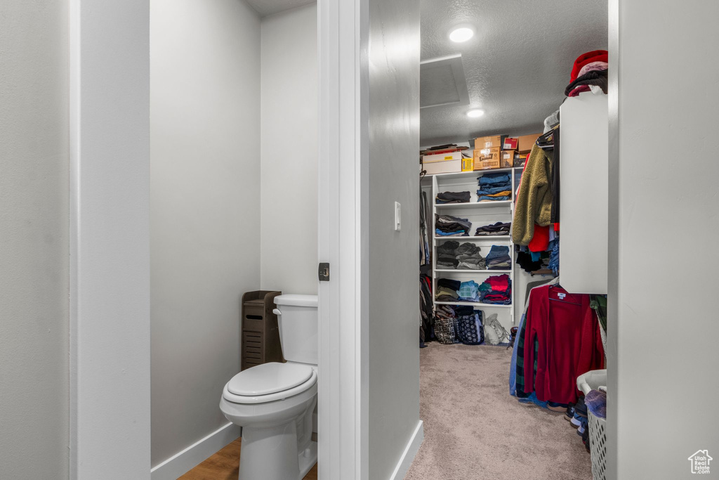 Bathroom with baseboards, toilet, a spacious closet, and a textured ceiling