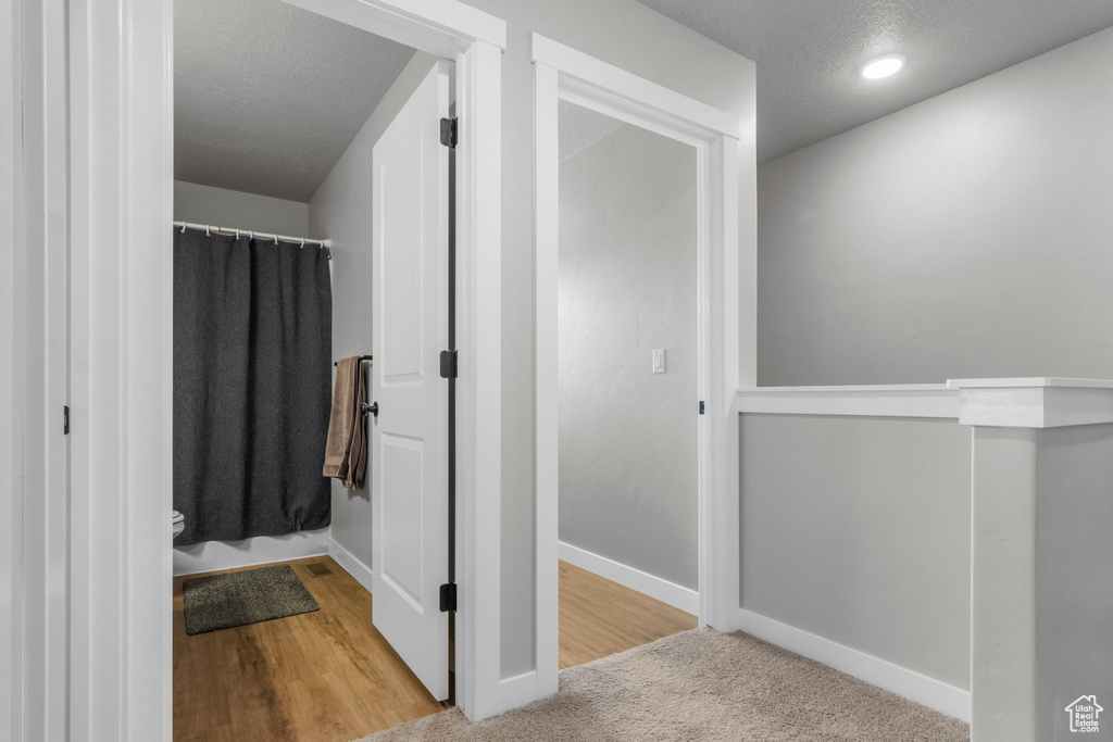Bathroom with curtained shower, baseboards, and a textured ceiling