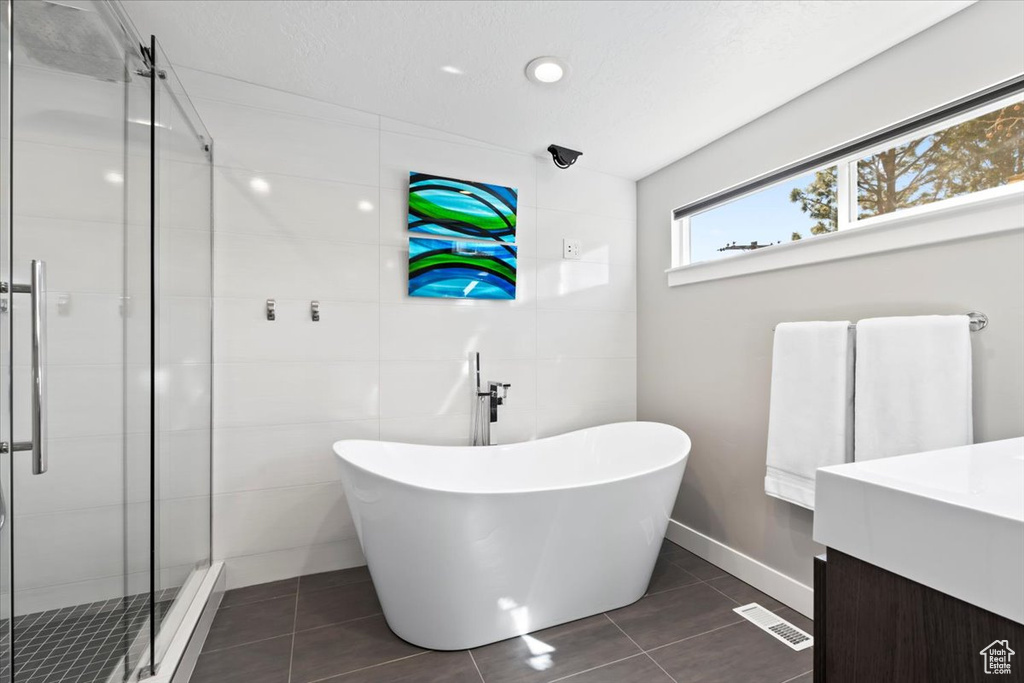 Full bathroom with tile patterned flooring, a soaking tub, a stall shower, and tile walls