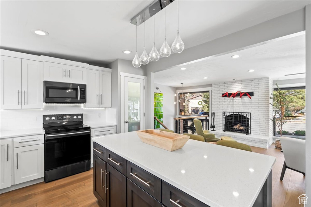 Kitchen featuring stainless steel microwave, electric range, a healthy amount of sunlight, and white cabinetry