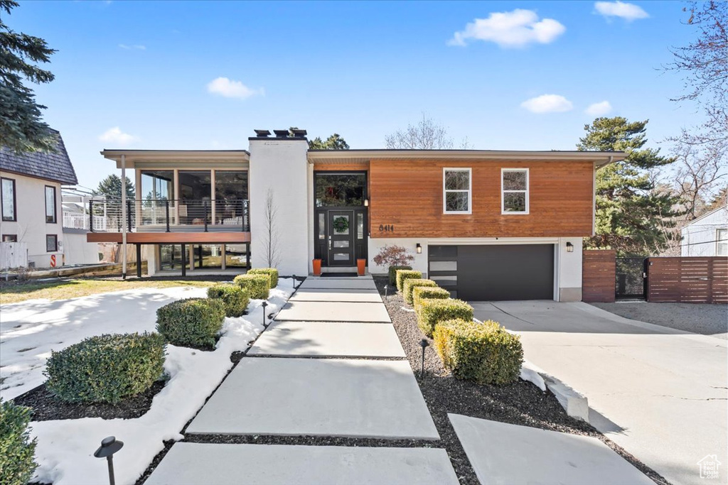 View of front of property with fence, a chimney, a garage, driveway, and a gate