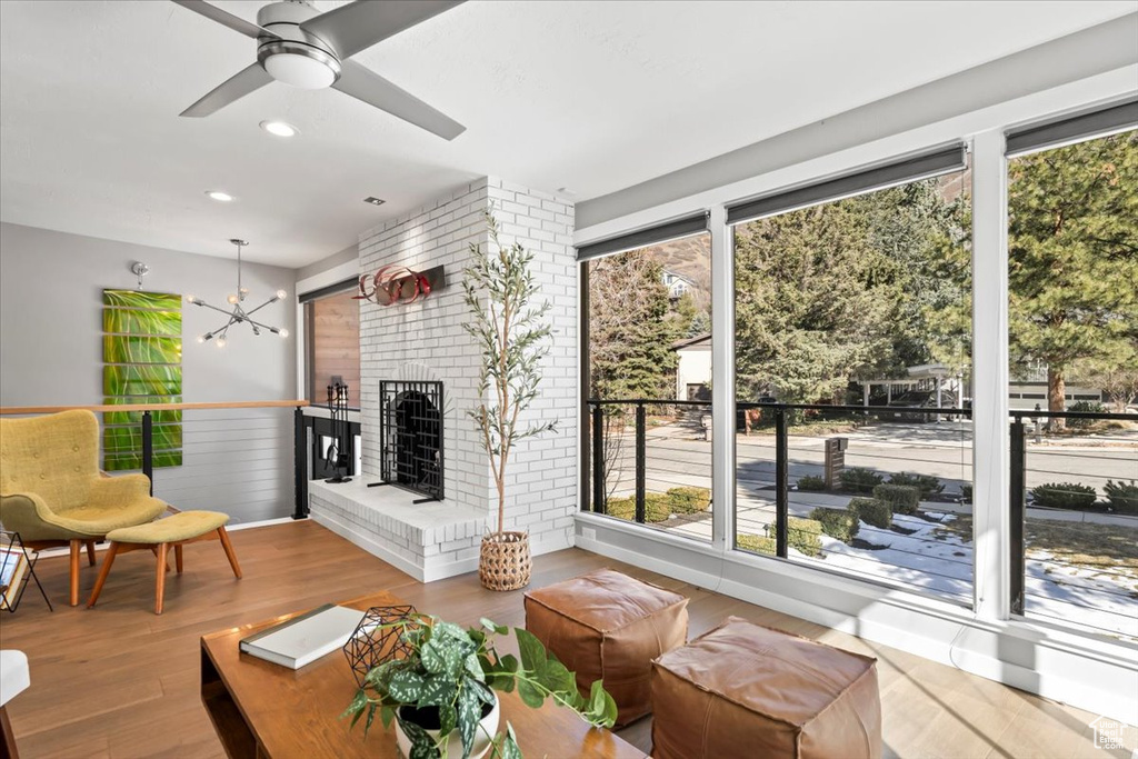Interior space with a fireplace, ceiling fan with notable chandelier, recessed lighting, and wood finished floors