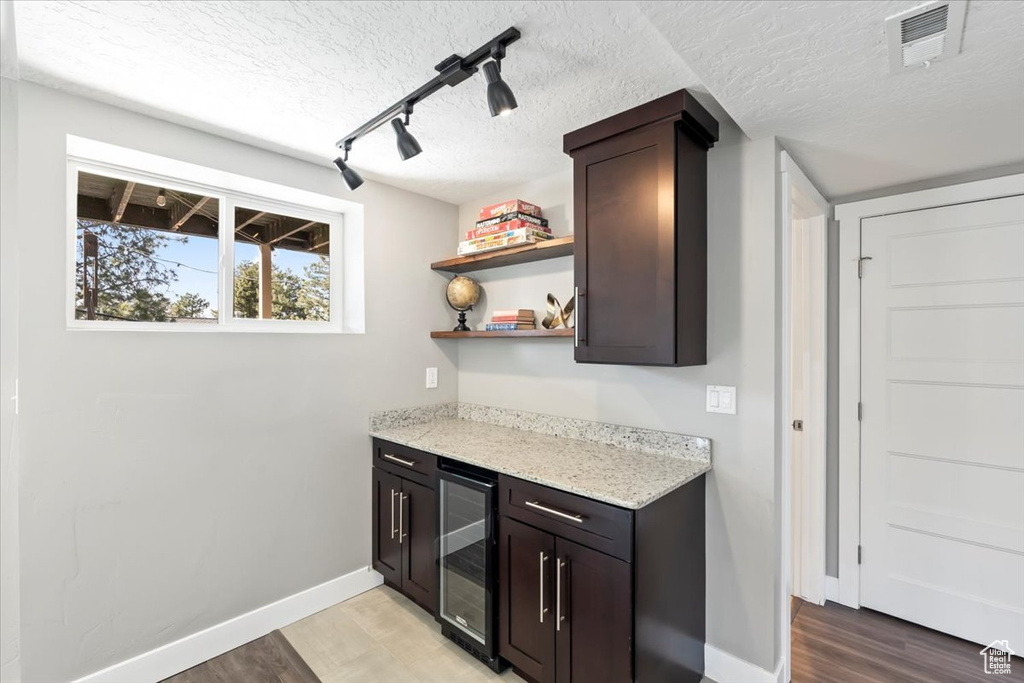 Bar featuring visible vents, a textured ceiling, wine cooler, light wood-style floors, and baseboards