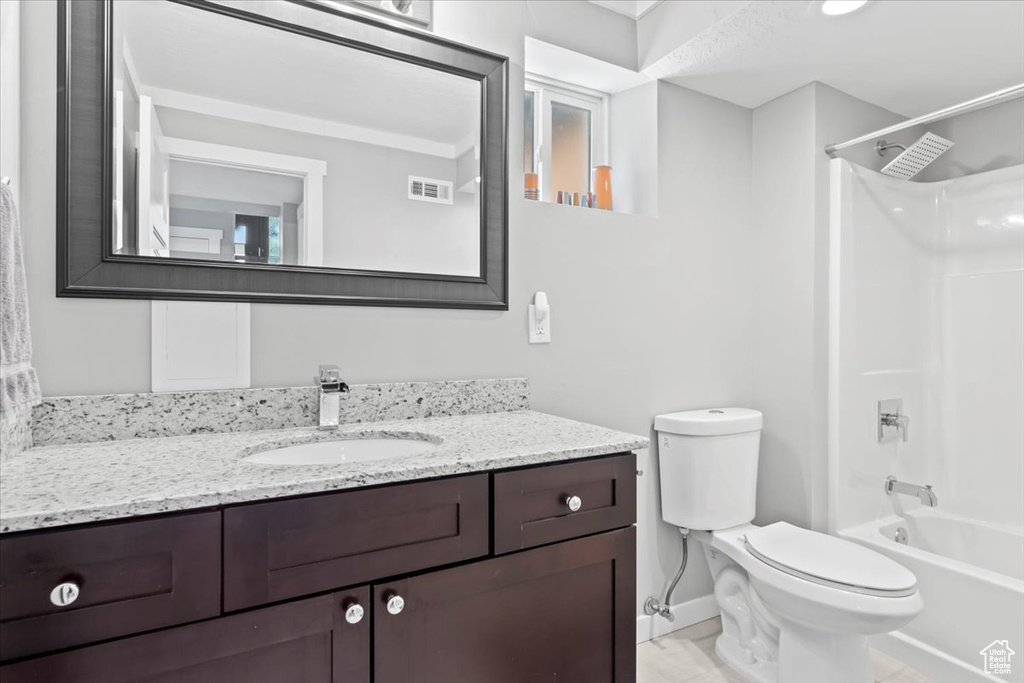 Full bath with visible vents, toilet, shower / washtub combination, baseboards, and vanity