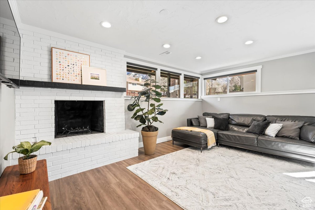 Living room featuring ornamental molding, wood finished floors, recessed lighting, a fireplace, and baseboards