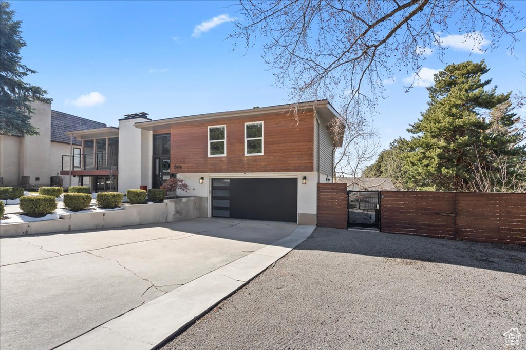View of front of property with fence, an attached garage, driveway, and a gate