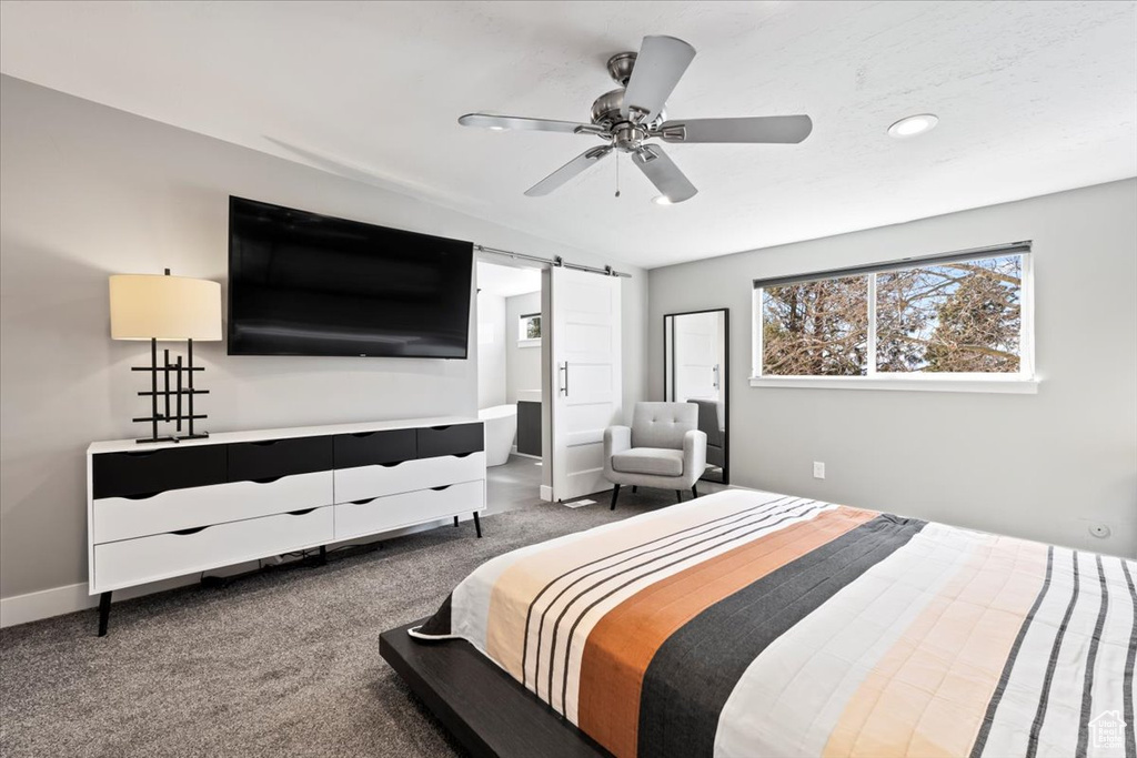 Carpeted bedroom with baseboards, a barn door, and a ceiling fan