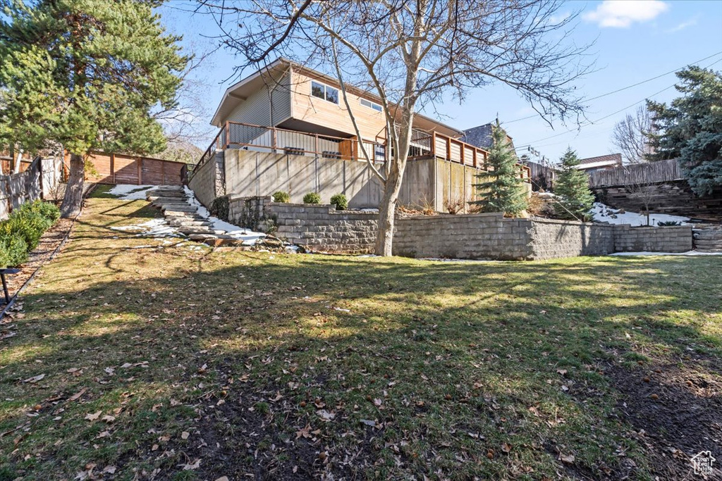 Rear view of property featuring stairway, a lawn, and fence
