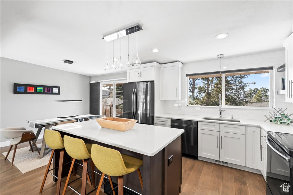 Kitchen with a sink, a kitchen island, appliances with stainless steel finishes, and dark wood finished floors