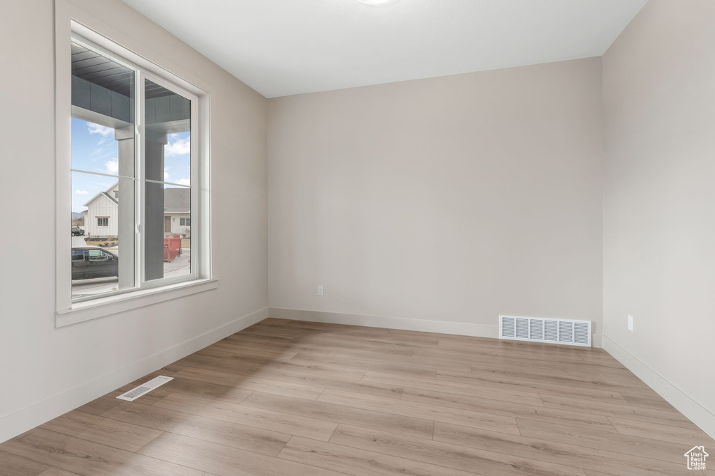 Empty room with visible vents, baseboards, and light wood-style floors