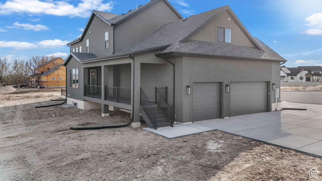Exterior space featuring a sunroom, a shingled roof, stucco siding, concrete driveway, and a garage