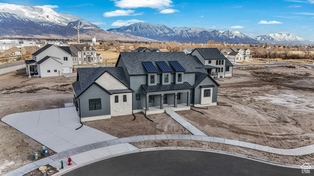View of front of property with a standing seam roof, a porch, a shingled roof, a mountain view, and metal roof