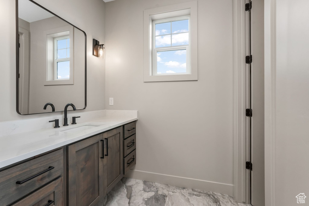 Bathroom featuring vanity, plenty of natural light, baseboards, and marble finish floor