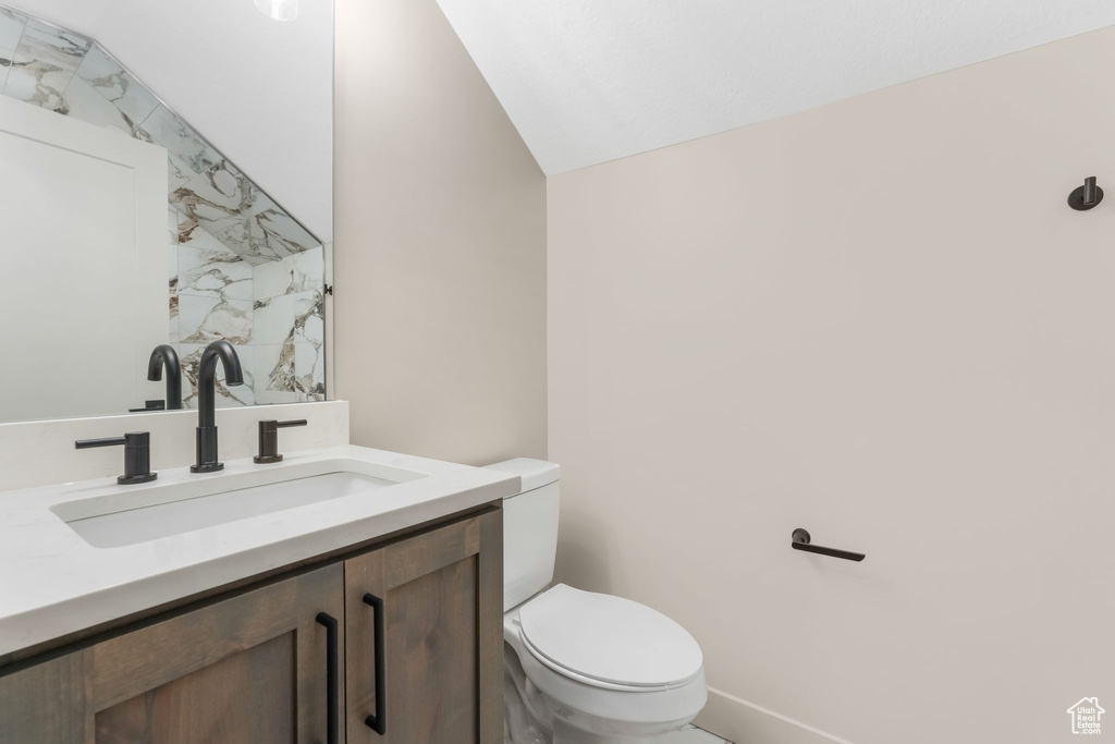 Bathroom with toilet, vanity, and vaulted ceiling