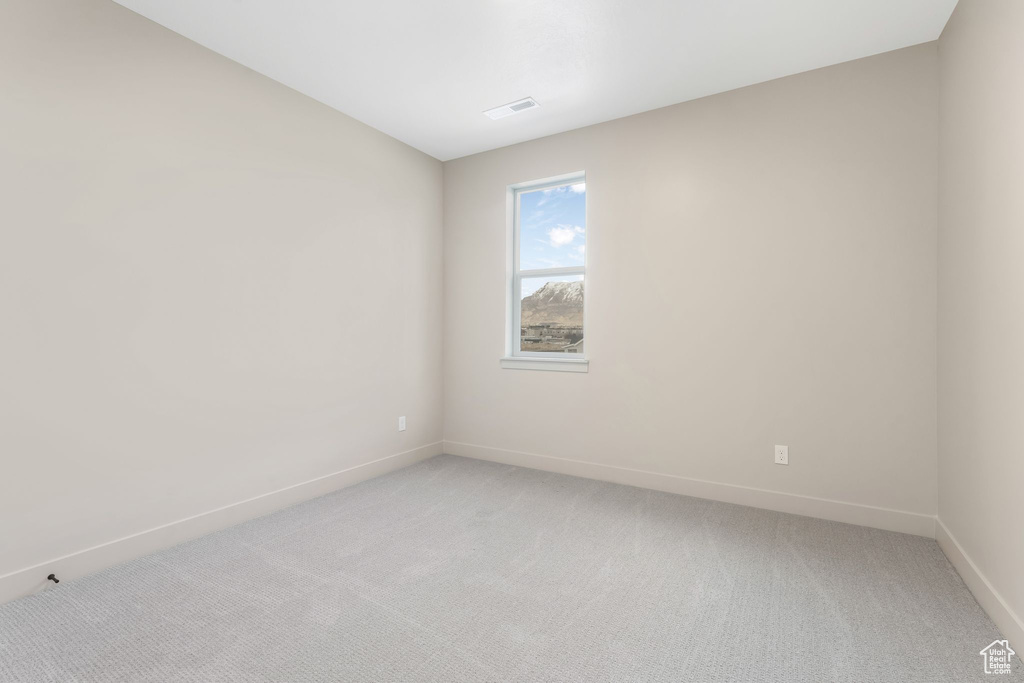 Empty room with light colored carpet and baseboards