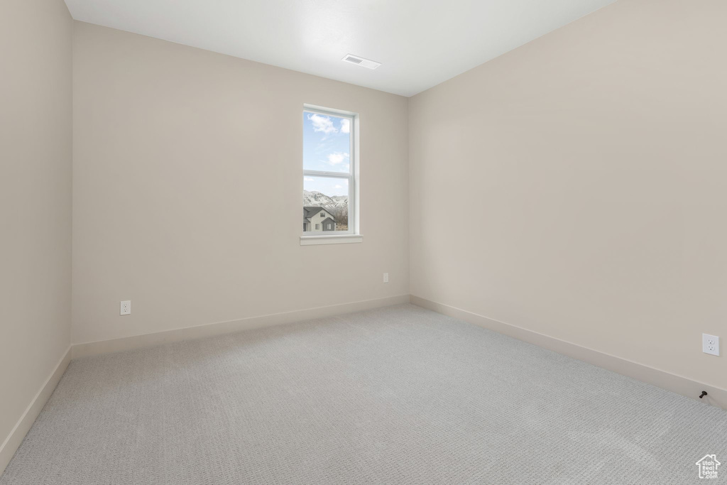 Spare room with baseboards, visible vents, and light carpet