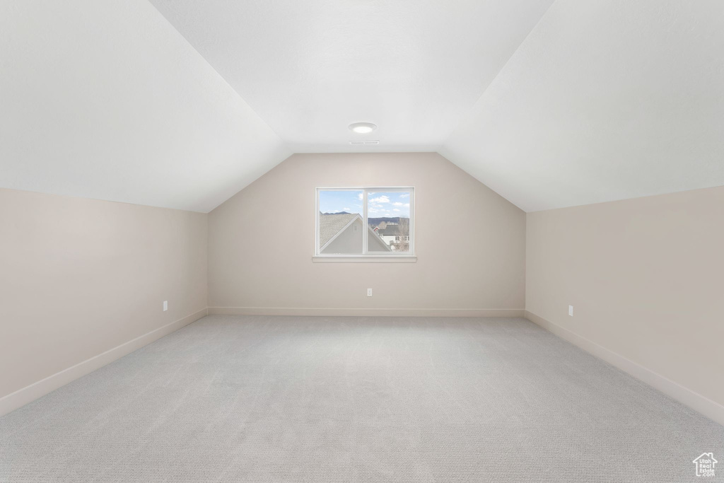 Bonus room featuring baseboards, light carpet, and vaulted ceiling