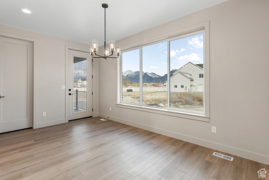 Unfurnished dining area featuring baseboards, visible vents, an inviting chandelier, light wood-style flooring, and a mountain view