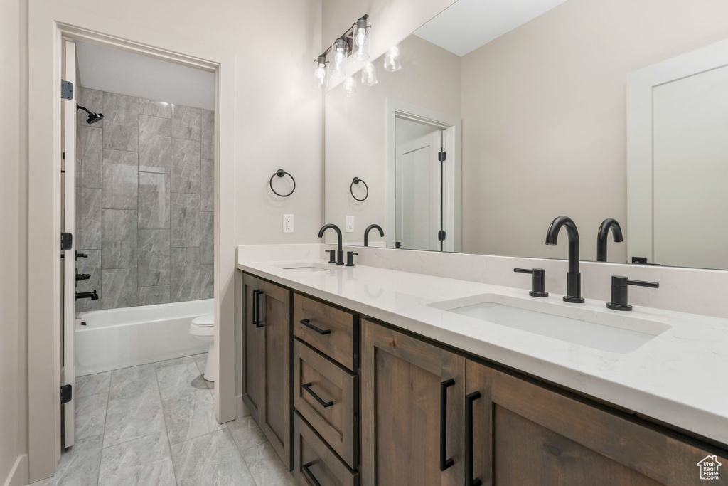 Bathroom featuring a sink, toilet, shower / washtub combination, and double vanity