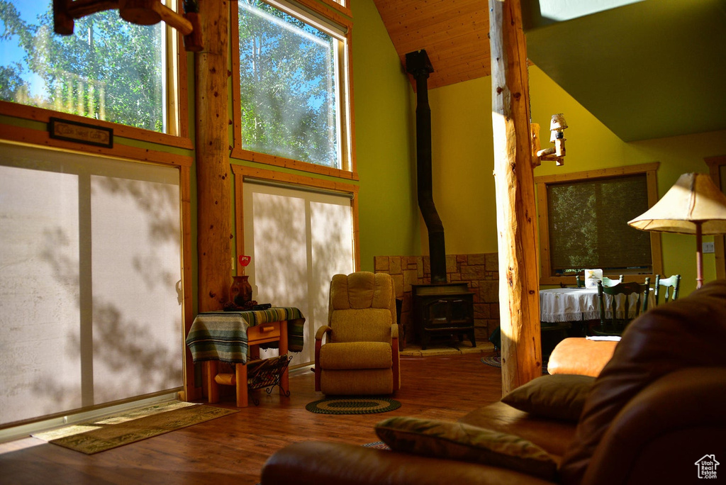 Living room featuring a wood stove, wood finished floors, and high vaulted ceiling