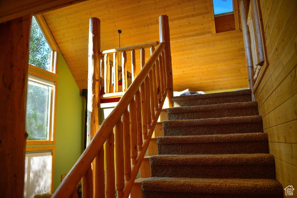 Staircase featuring wood walls, wooden ceiling, and lofted ceiling