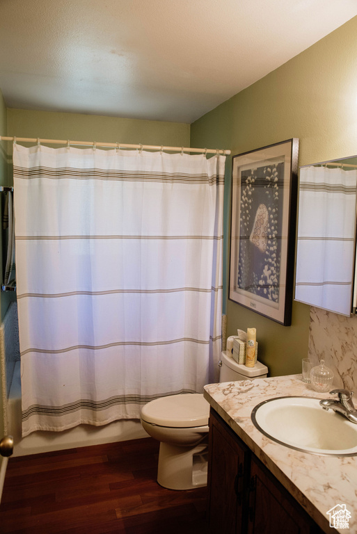 Bathroom featuring vanity, toilet, wood finished floors, and shower / bath combo