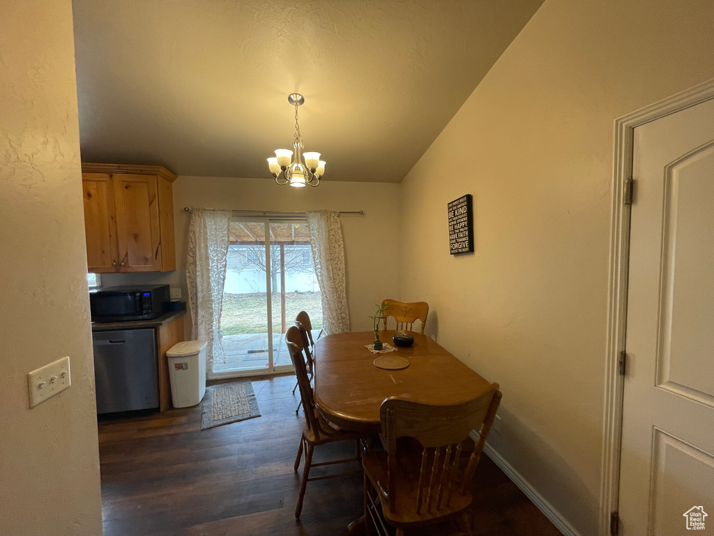 Dining space with vaulted ceiling, baseboards, dark wood-type flooring, and a chandelier